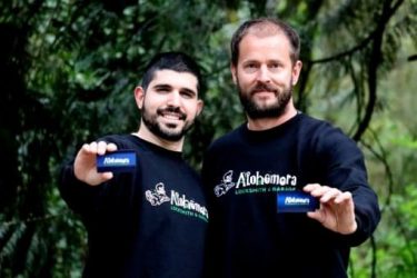 Two Alohomora Portland Locksmith Technicians smiling and holding out business cards in Portland Oregon
