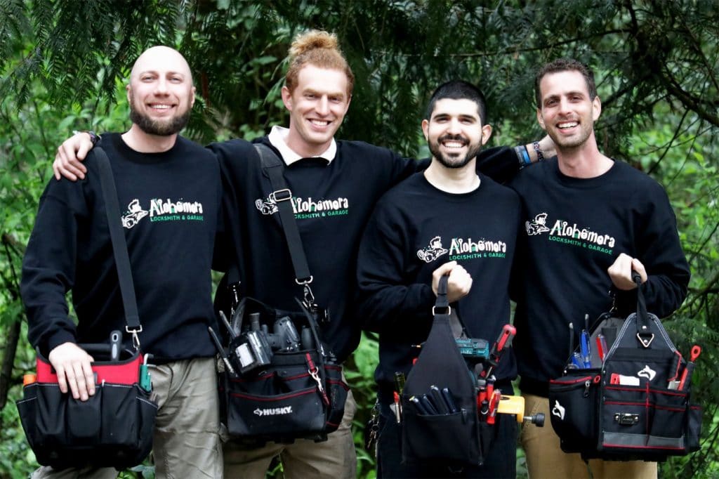 Four men holding tool bags wearing Alohomora shirts