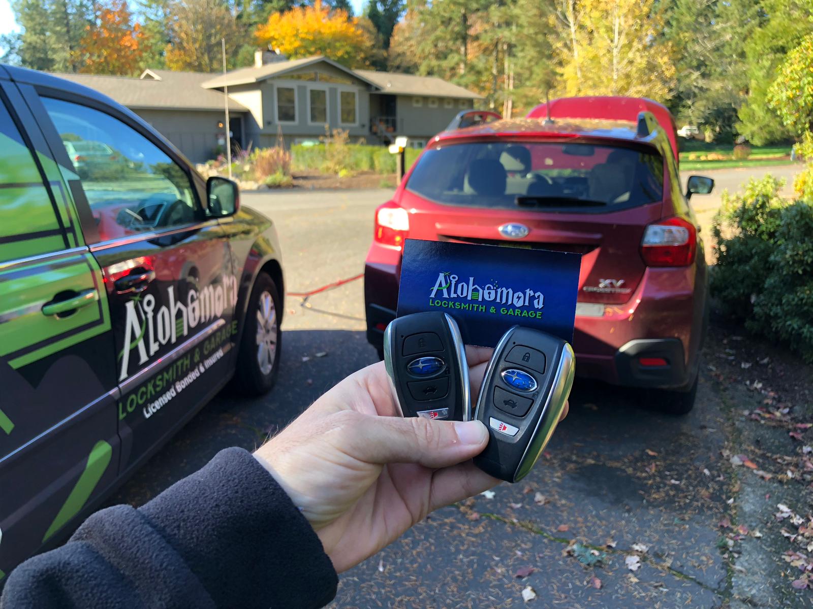 Alohomora Locksmith Portland Business Card with two keys in front of a Subaru car | Portland Automotive Locksmith